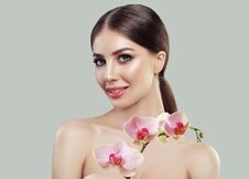 Cute Smiling Woman With Healthy Skin And Pink Orchid Flowers Royalty Free Stock Photos