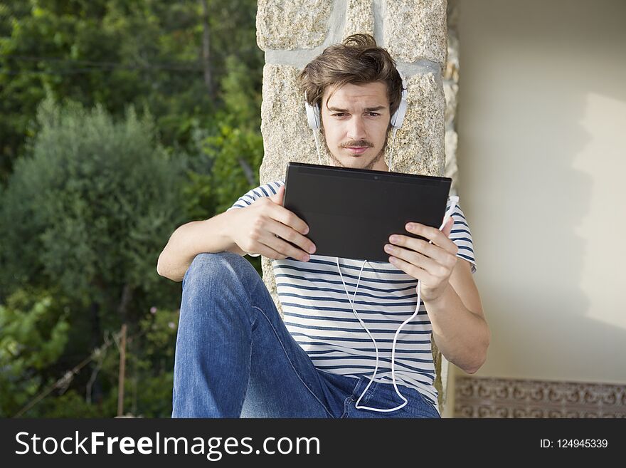 Young man listening music with headphones, outdoor