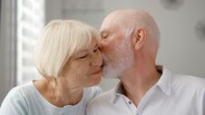 Portrait Of Happy Senior Couple At Home. Senior Man Expresses His Emotions And Kisses His Wife Royalty Free Stock Photos