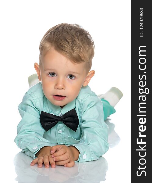 Adorable little boy lying on the floor holding his face with both hands isolated on white background. Adorable little boy lying on the floor holding his face with both hands isolated on white background