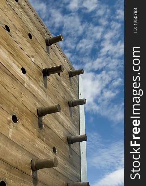 A wooden climbing wall with pegs.