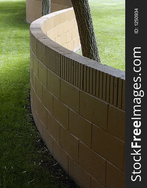 An unusual S-shaped brick wall among tree trunks and well cared for lawn. An unusual S-shaped brick wall among tree trunks and well cared for lawn