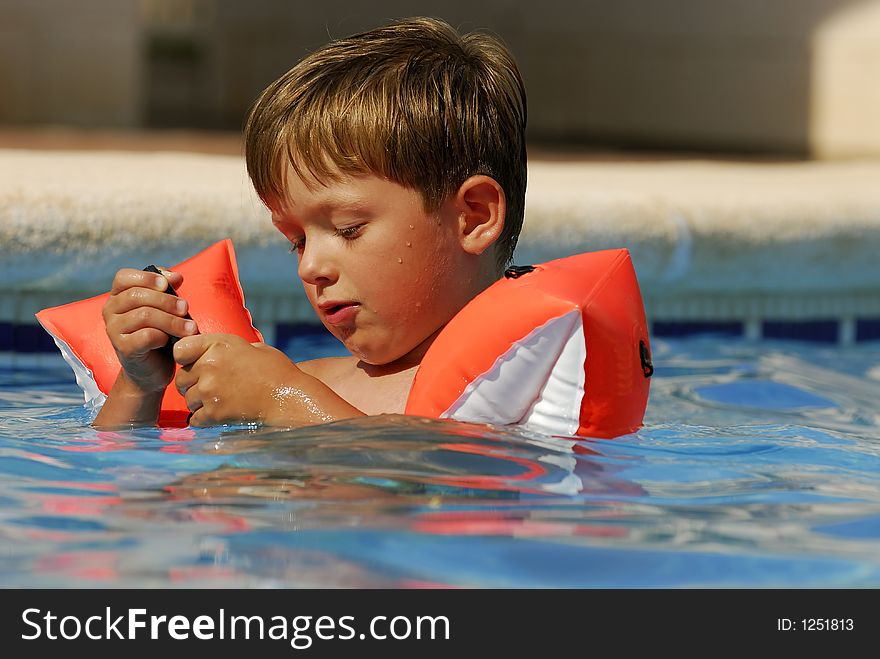 Boy child makes a call with a cell-phone in a swimming-pool. Boy child makes a call with a cell-phone in a swimming-pool