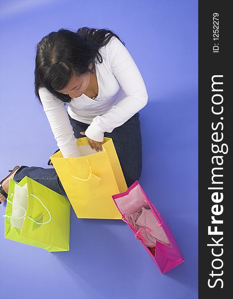 Woman sitting with shopping bags over blue background