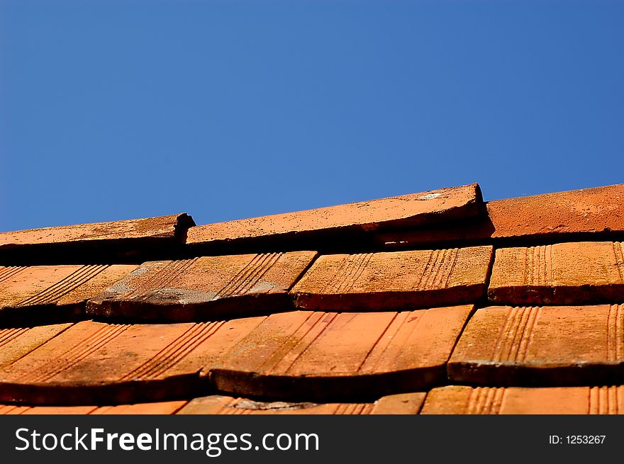 Orange/red roof of old country house with blue sky as background. Orange/red roof of old country house with blue sky as background