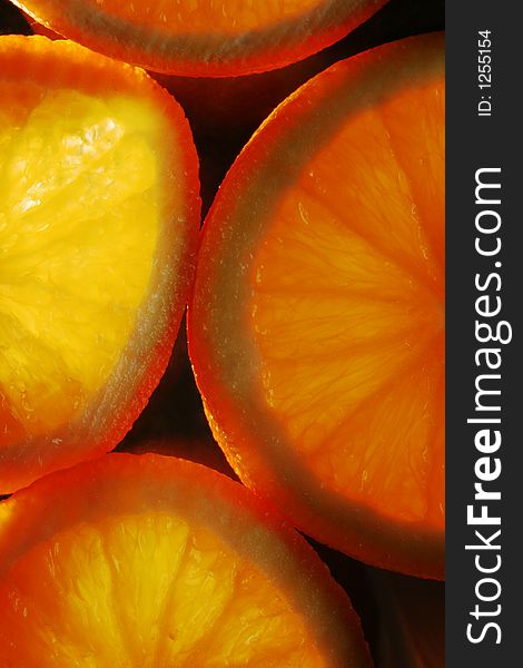 Slices of orange on black background, lit from underneath. Slices of orange on black background, lit from underneath