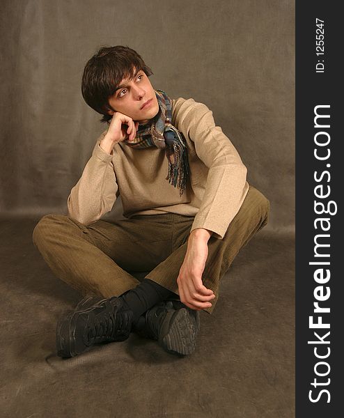 The young man in a scarf sitting on a floor. The young man in a scarf sitting on a floor