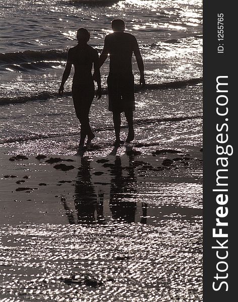 Young couple walking in the surf at the beach. Young couple walking in the surf at the beach.