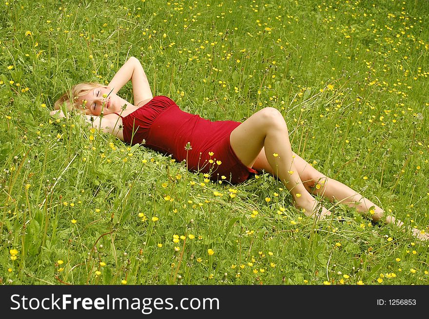 Red haired girl lying between yellow flowers and grass. Red haired girl lying between yellow flowers and grass.