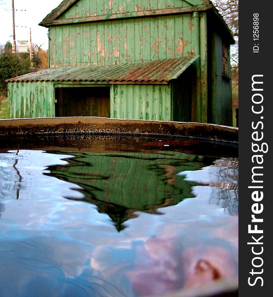An old shed in the background with reflection of shed in water in foreground. An old shed in the background with reflection of shed in water in foreground