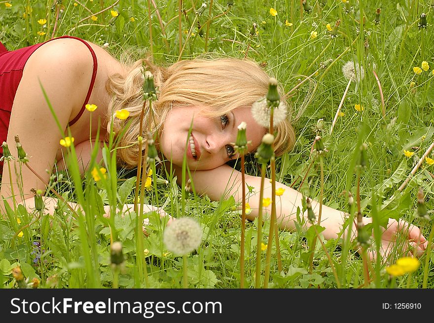 Red haired girl lying between yellow flowers and grass. Red haired girl lying between yellow flowers and grass.