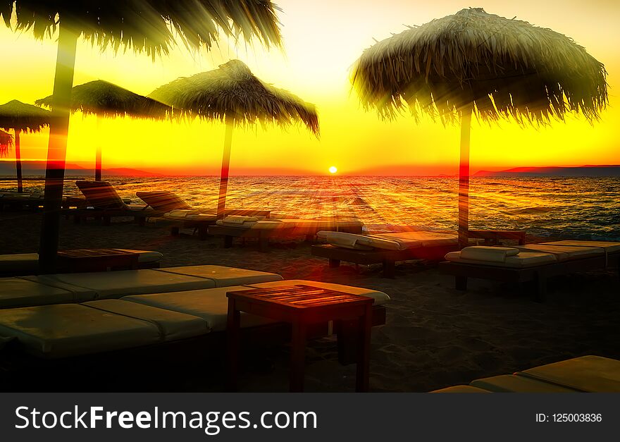 Sun rays cut through beach umbrellas at sunset sandy beach, Europe, Greece, Crete