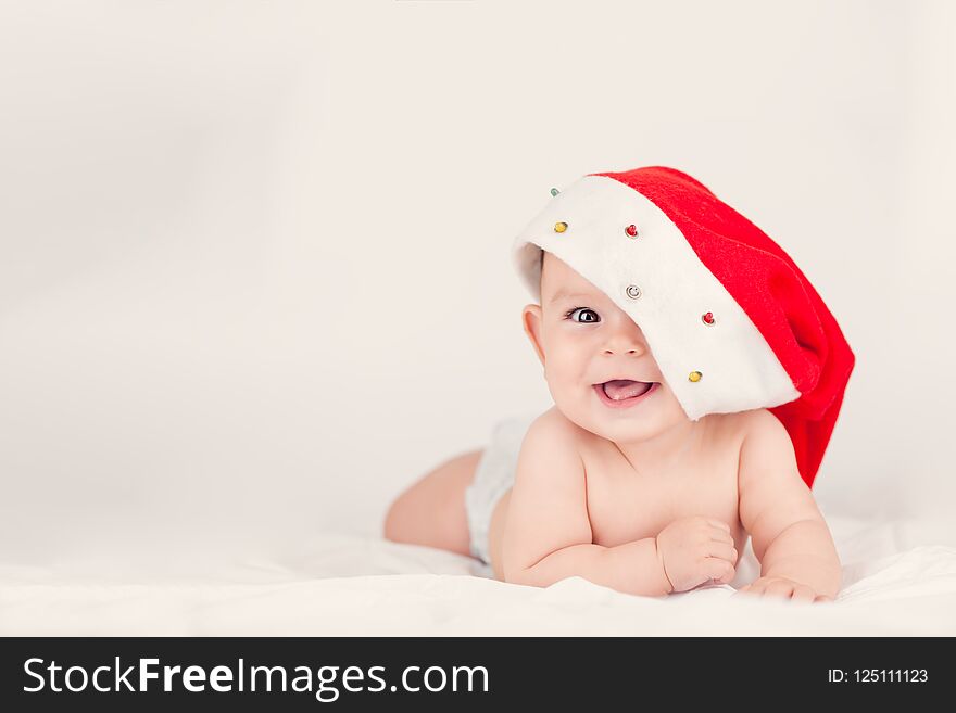 Xmas card with cute baby girl with santa hat on beige airy briht background with copy space