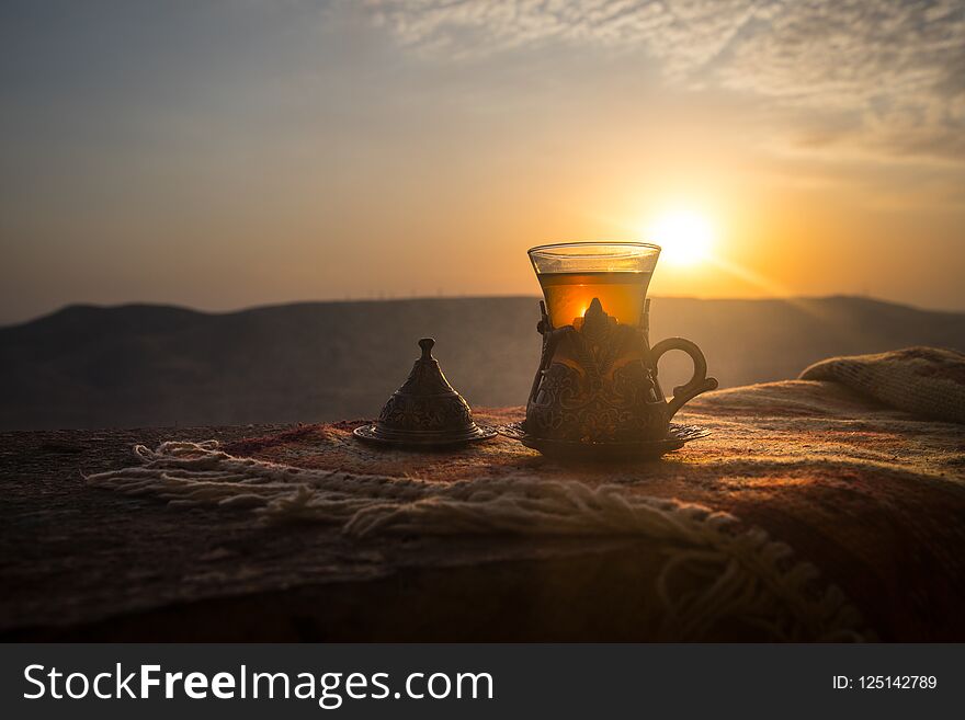 Arabian tea in glass on a eastern carpet. Eastern tea concept. Armudu traditional cup. Sunset background. Selective focus