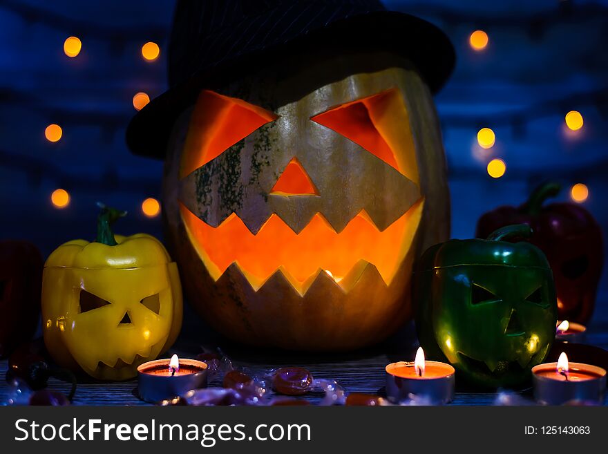 Close up photo of spoofy face of jack-o-lantern, peppers with scary faces, candlelight, bokeh effect, candies