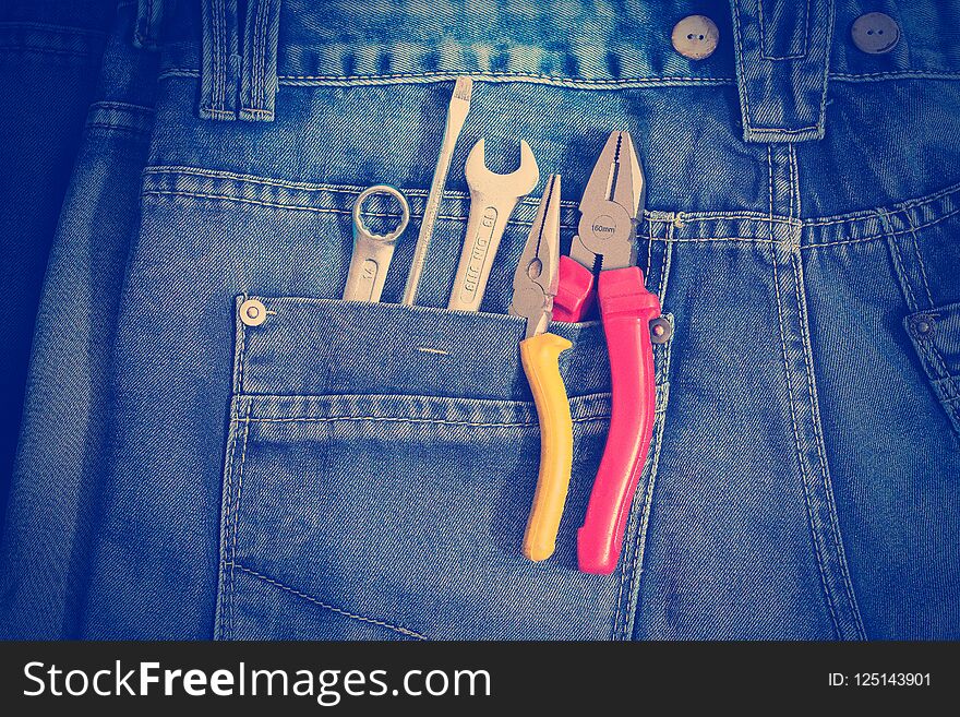 Several tools on a denim workers pocket toned with a retro vintage instagram filter effect app or action