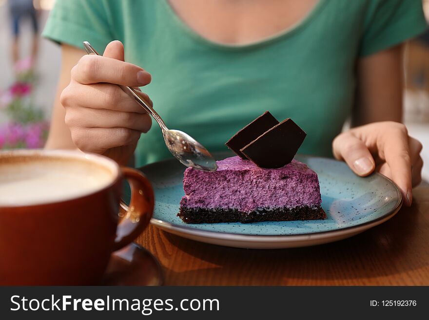 Woman eating slice of berry cheesecake at table