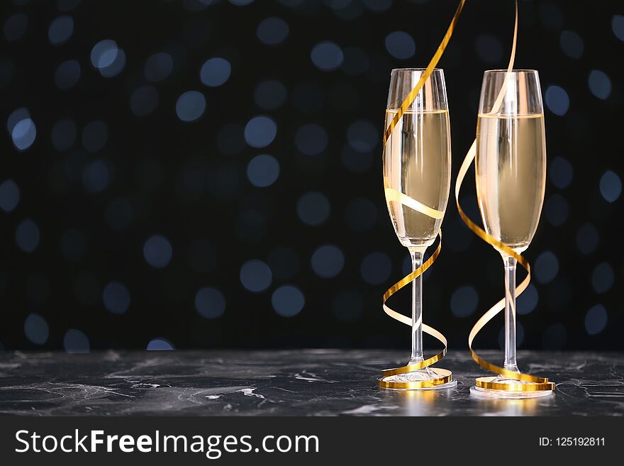 Glasses with champagne and space for text against blurred Christmas lights