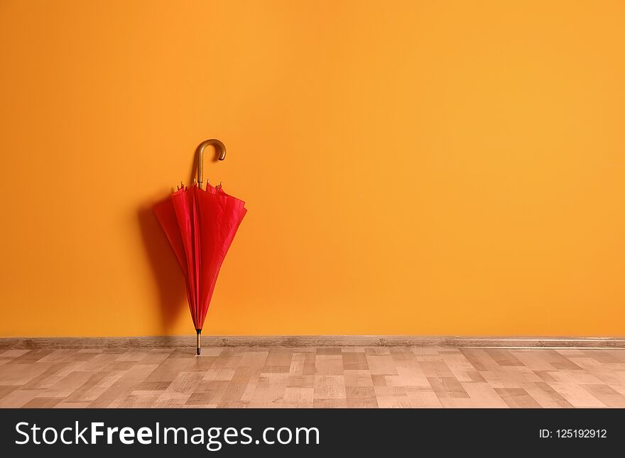 Beautiful umbrella on floor near color wall with space for design