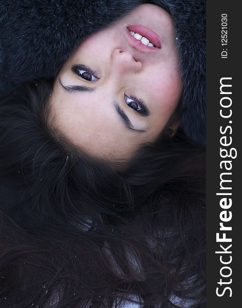 Face portrait of young attractive brunette woman lying on the snow. Perfect hair texture. Outdoor winter photo. Face portrait of young attractive brunette woman lying on the snow. Perfect hair texture. Outdoor winter photo.