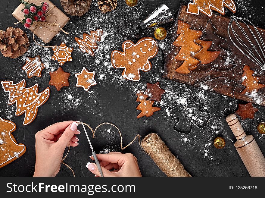 Christmas gift gingerbread on dark background. Biscuits in festive packaging. Woman is packaging Christmas gingerbread