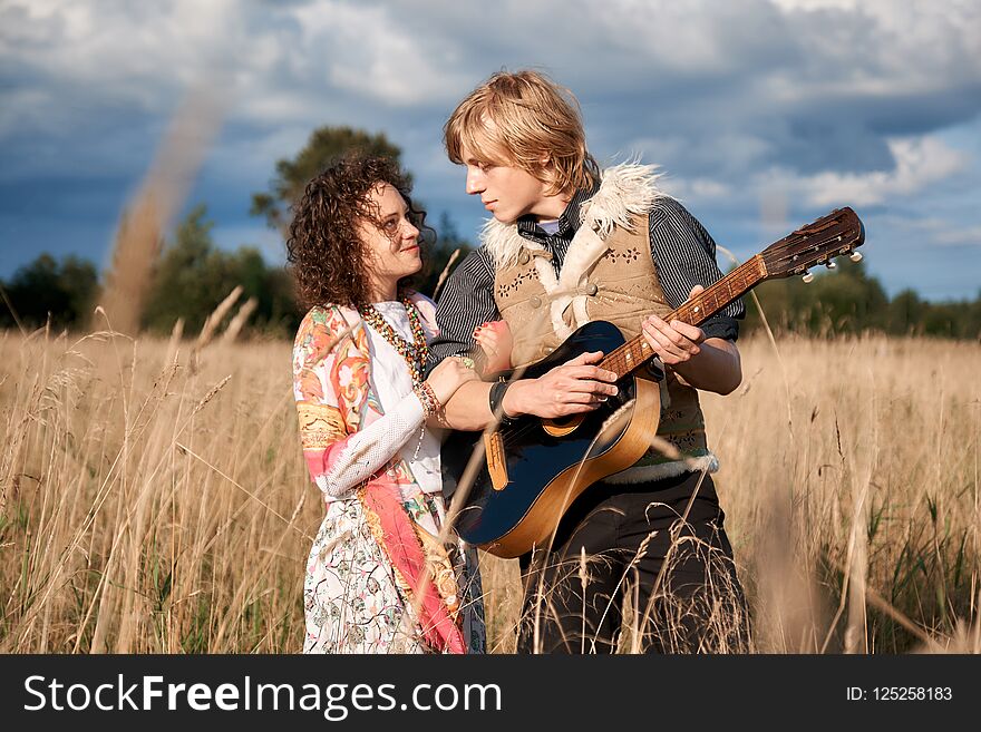 Boho style attractive couple in love posing on the autumn field.