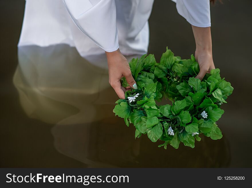 Close-up of woman in white dress in the water. Art Woman with wreath in river. Wet witch Girl in the lake