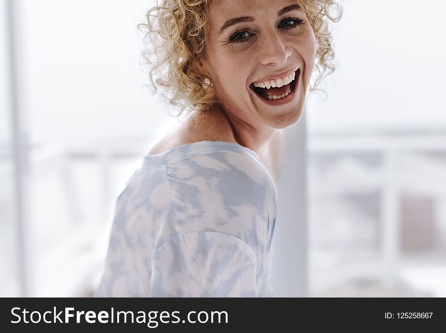 Close of a woman at home smiling. Woman with curly brown hair laughing. Close of a woman at home smiling. Woman with curly brown hair laughing.