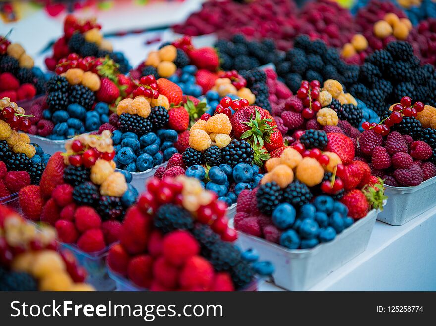 Fresh different berries in the plastic cup at Europe street berries and exotic fruits at market streetshop. Assortment festive appetizers in the cup, selective focus