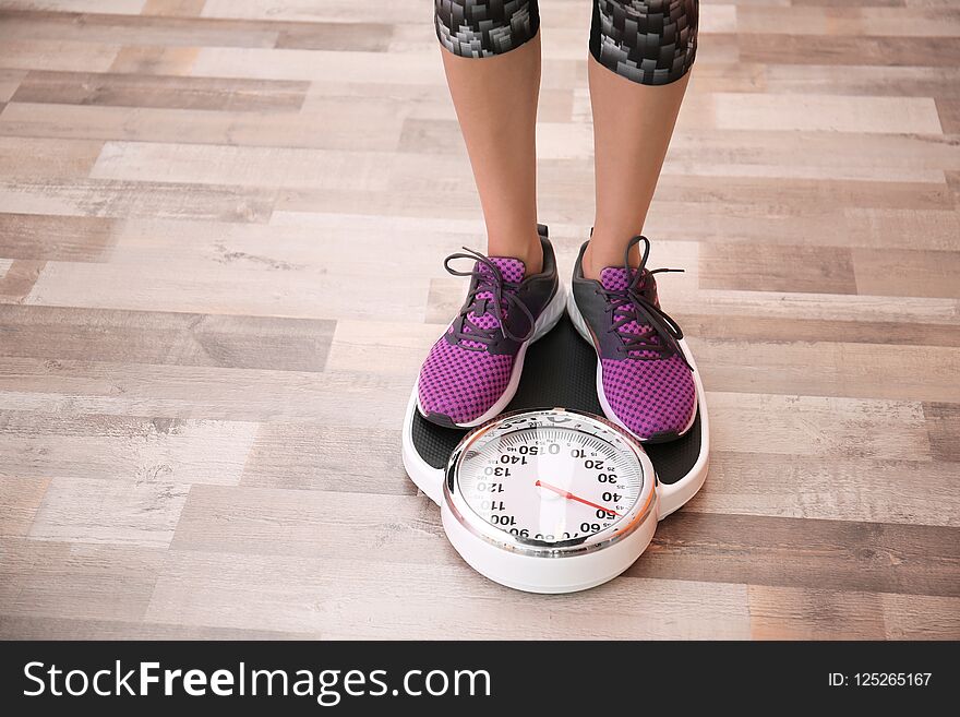 Woman measuring her weight using scales on floor