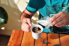 A Man In A Cafe Pours Cream Into A Cup Of Coffee In The Morning. Breakfast. Stock Images
