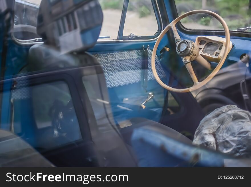 Side part of bright blue old automobile with wheel in window