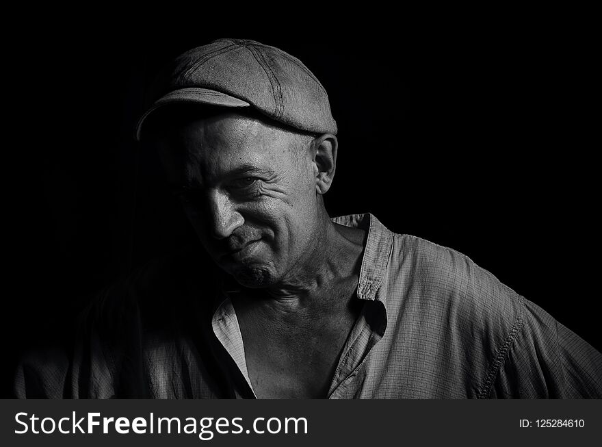 Portrait of an elderly man in a cap on a dark background . Portrait of an elderly man in a cap on a dark background .