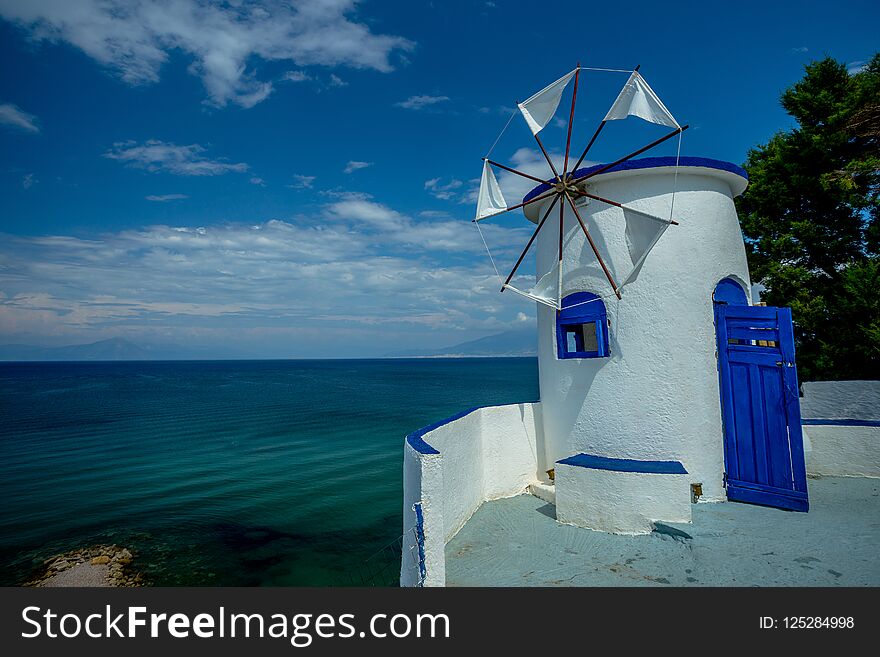 Traditional Greek White Windmill on the Sea Shore on a Bright Sunny Day
