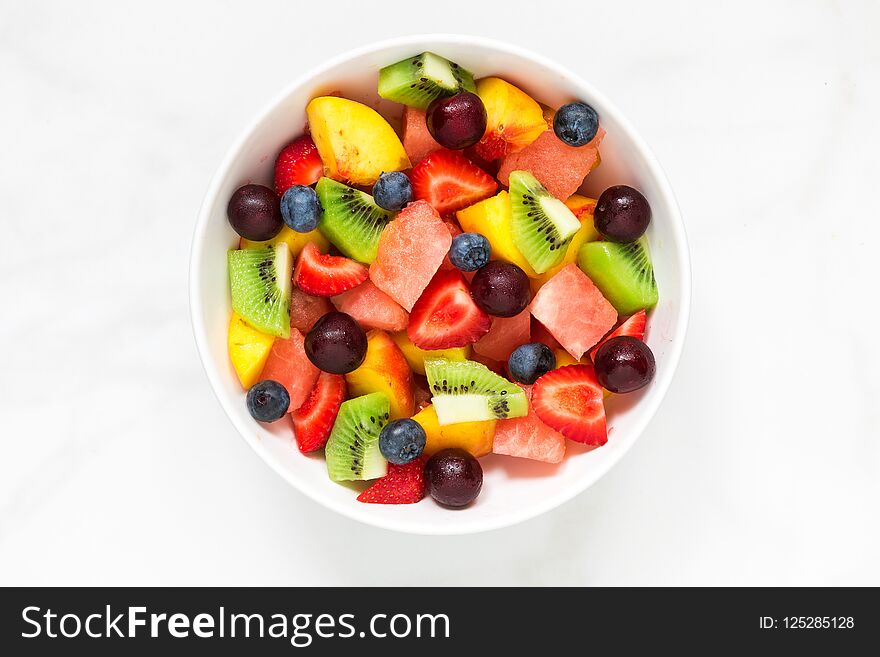 Bowl of healthy fresh fruit salad on white marble background. healthy food