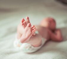 Health Concept - Closeup Of Legs Of A Newborn Baby Lying On Whit Royalty Free Stock Photography