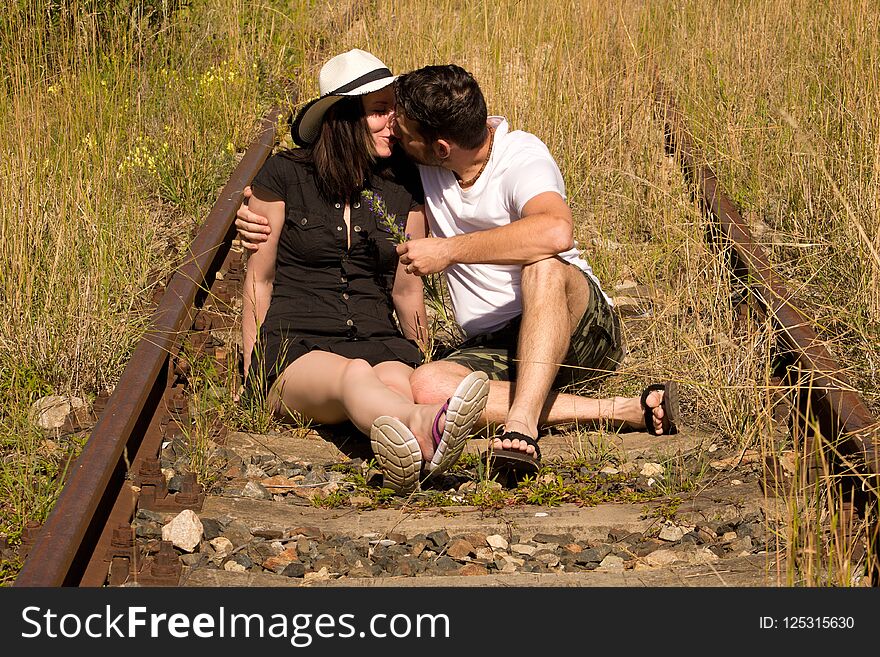 Young couple in embrace sitting on rails.