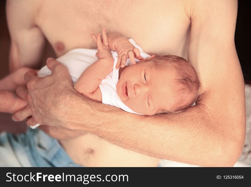 Peaceful baby lying in the arms of his father. Peaceful baby lying in the arms of his father
