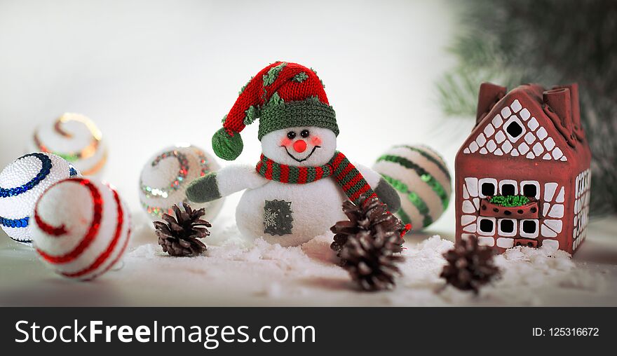 Toy snowman and a gingerbread house on a light background.