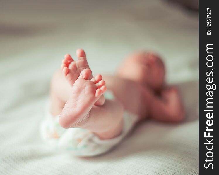 Health concept - closeup of legs of a newborn baby lying on white blanket.the photo has a empty space for your text