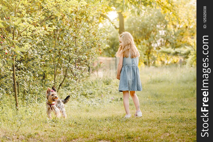 Little girl running with the dog in the countryside