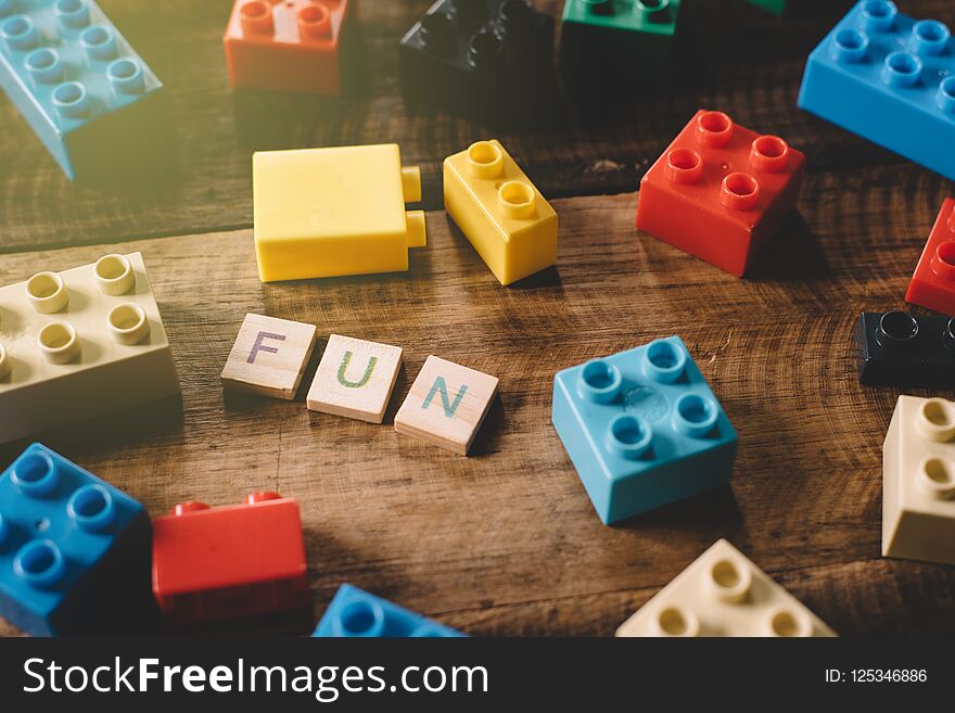 Plastic toy bricks with alphabet tiles word FUN on wooden table