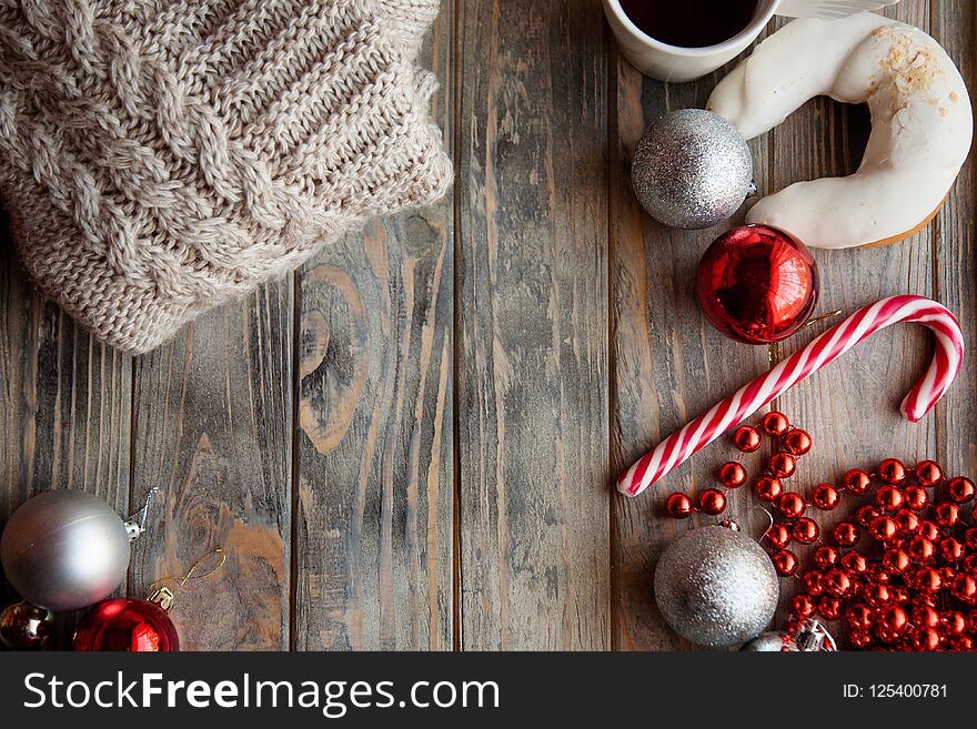 Festive christmas decor background. seasonal design with holiday adornments and embellishments. knitted sweater shiny balls beads and candy cane on grey wooden backdrop. Festive christmas decor background. seasonal design with holiday adornments and embellishments. knitted sweater shiny balls beads and candy cane on grey wooden backdrop.