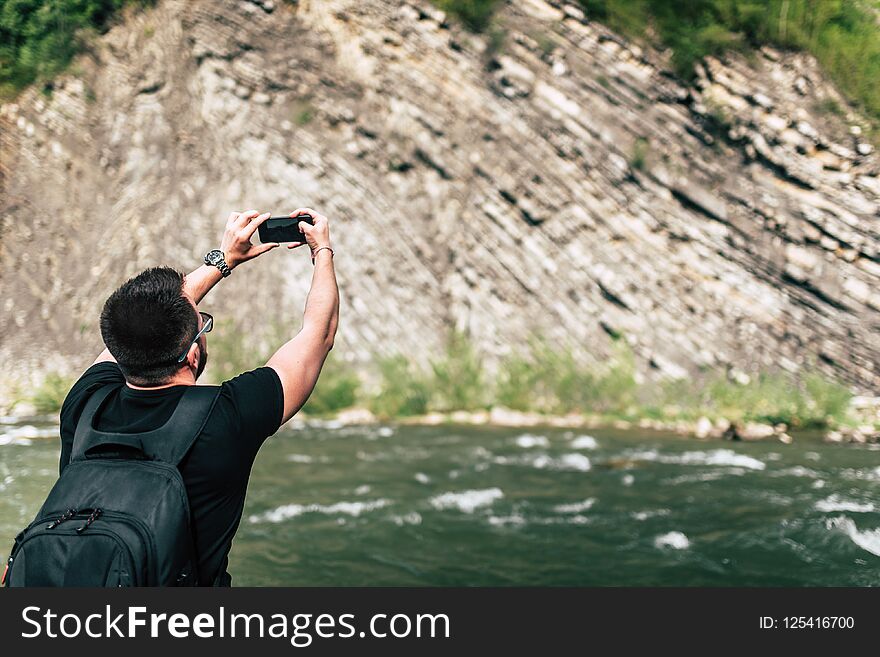 Yong traveler taking photo near mountain river