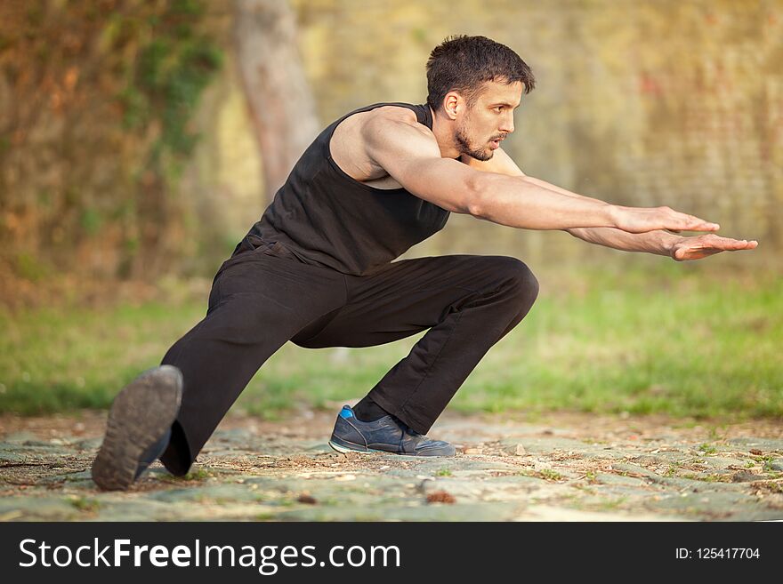 Young muscular man runner stretching legs before running, workout in nature. Young muscular man runner stretching legs before running, workout in nature