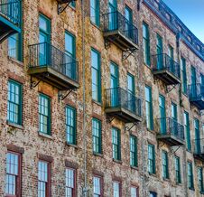 Old Brick Building With Red And Green Windows And Balconies Stock Photo