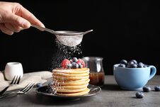 Woman Adding Sugar Powder To Tasty Pancakes With Berries On Plate Stock Photo