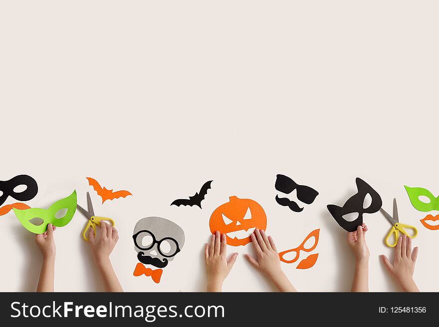 Halloween. The masks from paper on a white background which are cut out. Children`s hands. Halloween. The masks from paper on a white background which are cut out. Children`s hands.