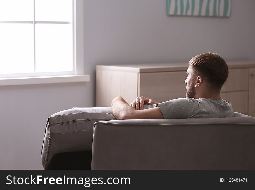 Depressed young man sitting in armchair