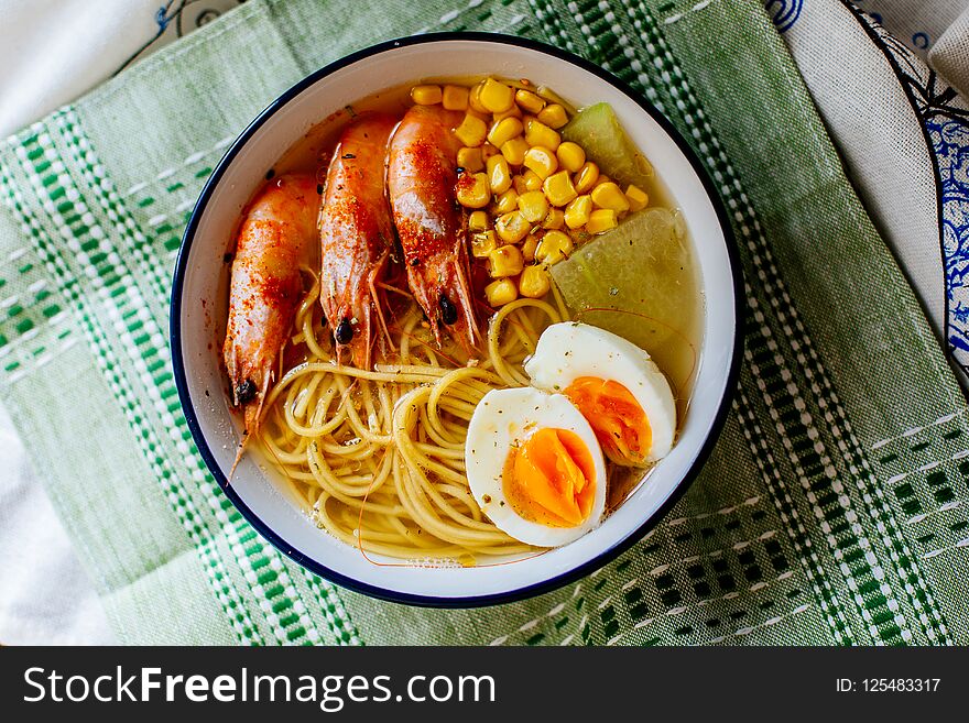 Asian food, Ramen noodle soup with prawn, corns and egg in white bowl.
